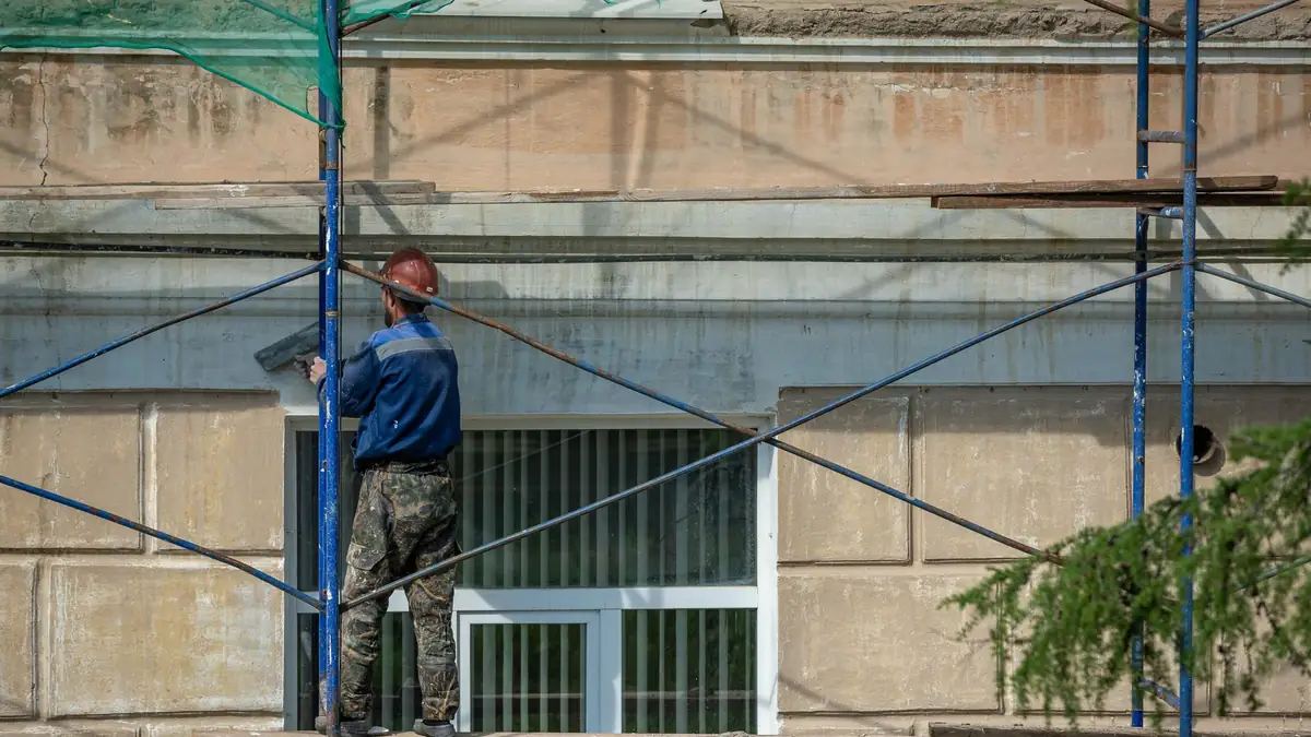 Εργάτης σε σκαλωσιά επισκευάζει πρόσοψη κτιρίου